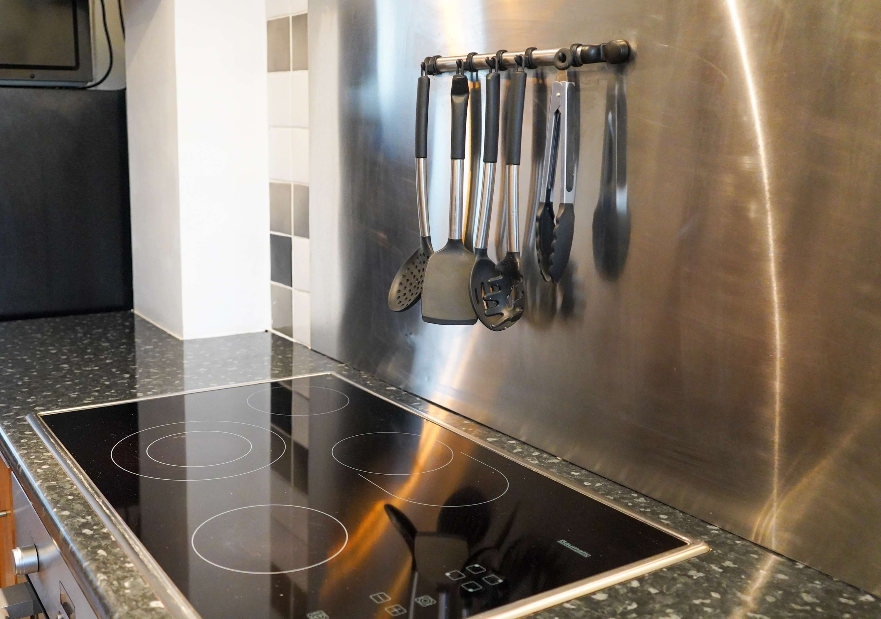 Une cuisine moderne dotée d’une hotte en acier inoxydable et d’une plaque de cuisson à induction noire.
