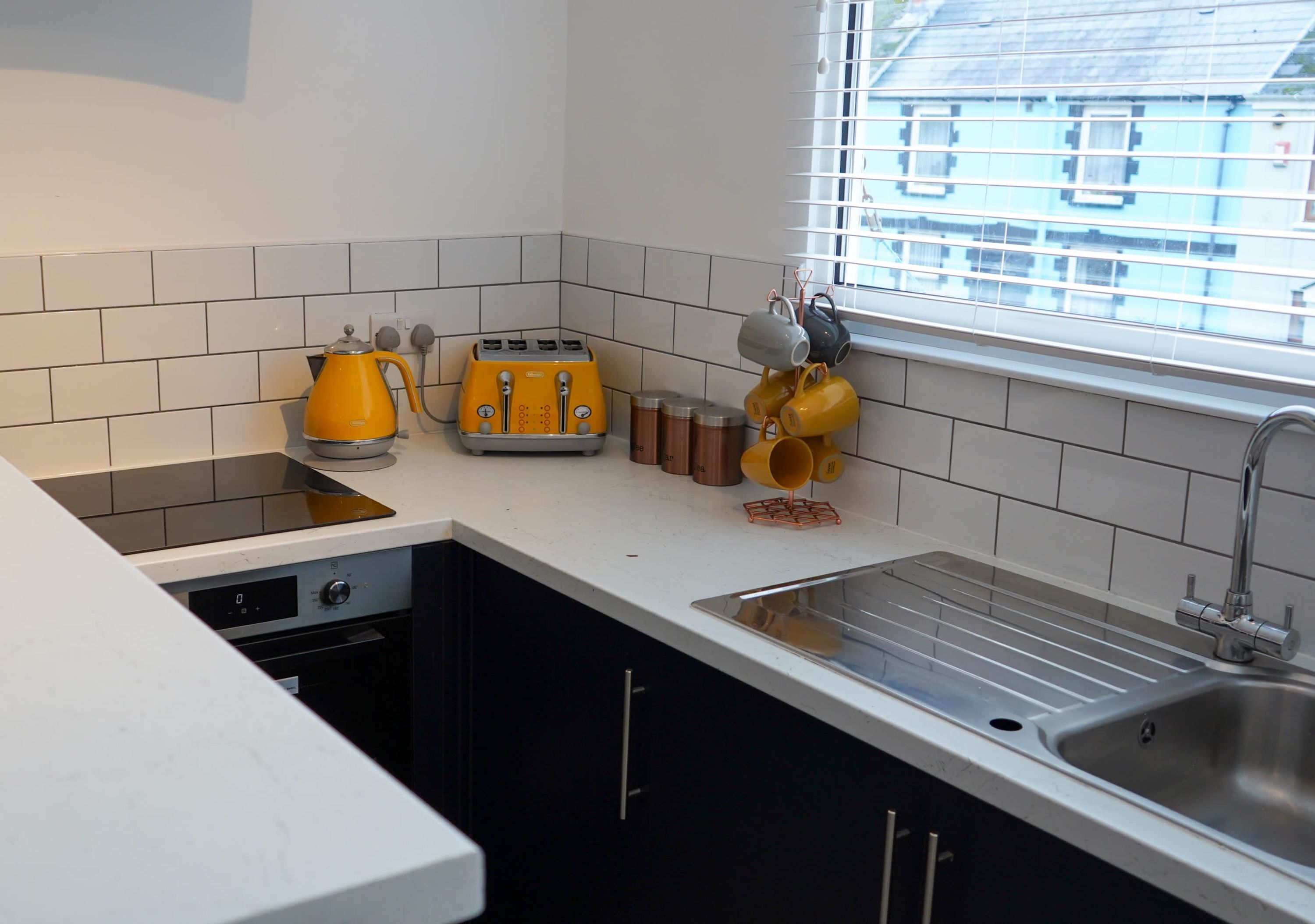 A kitchen with a toaster, kettle, and stacked mugs.