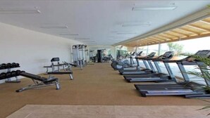 Une salle de sport équipée de tapis de course, d’haltères et d’appareils de musculation.