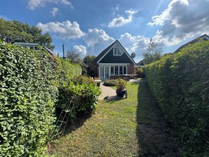 Ein Haus mit befestigter Auffahrt, einem Garten mit Topfpflanze und einer Satellitenschüssel auf dem Dach.