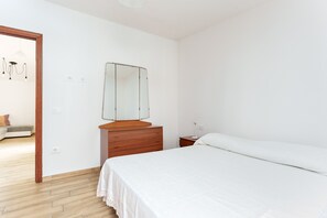 Un dormitorio con cama, cómoda de madera y espejo.