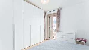 Een slaapkamer met een bed, een witte kledingkast, een nachtkastje en een raam met gordijnen.