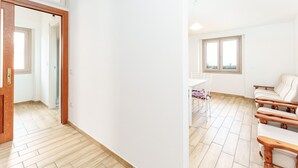 Een ruime kamer met houten vloer, een eettafel met stoelen, een bank en een raam met uitzicht.