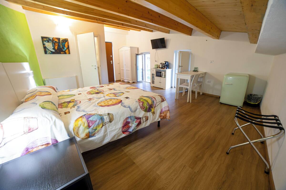 Ein Schlafzimmer mit einem Bett, einem Schreibtisch, einem Sessel, einem Fernseher und einem kleinen Kühlschrank.
