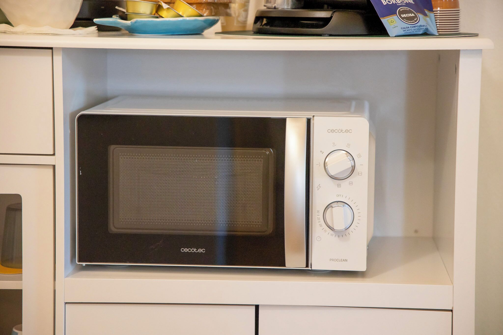 A compact microwave oven with a digital display and two control knobs, placed on a white countertop.