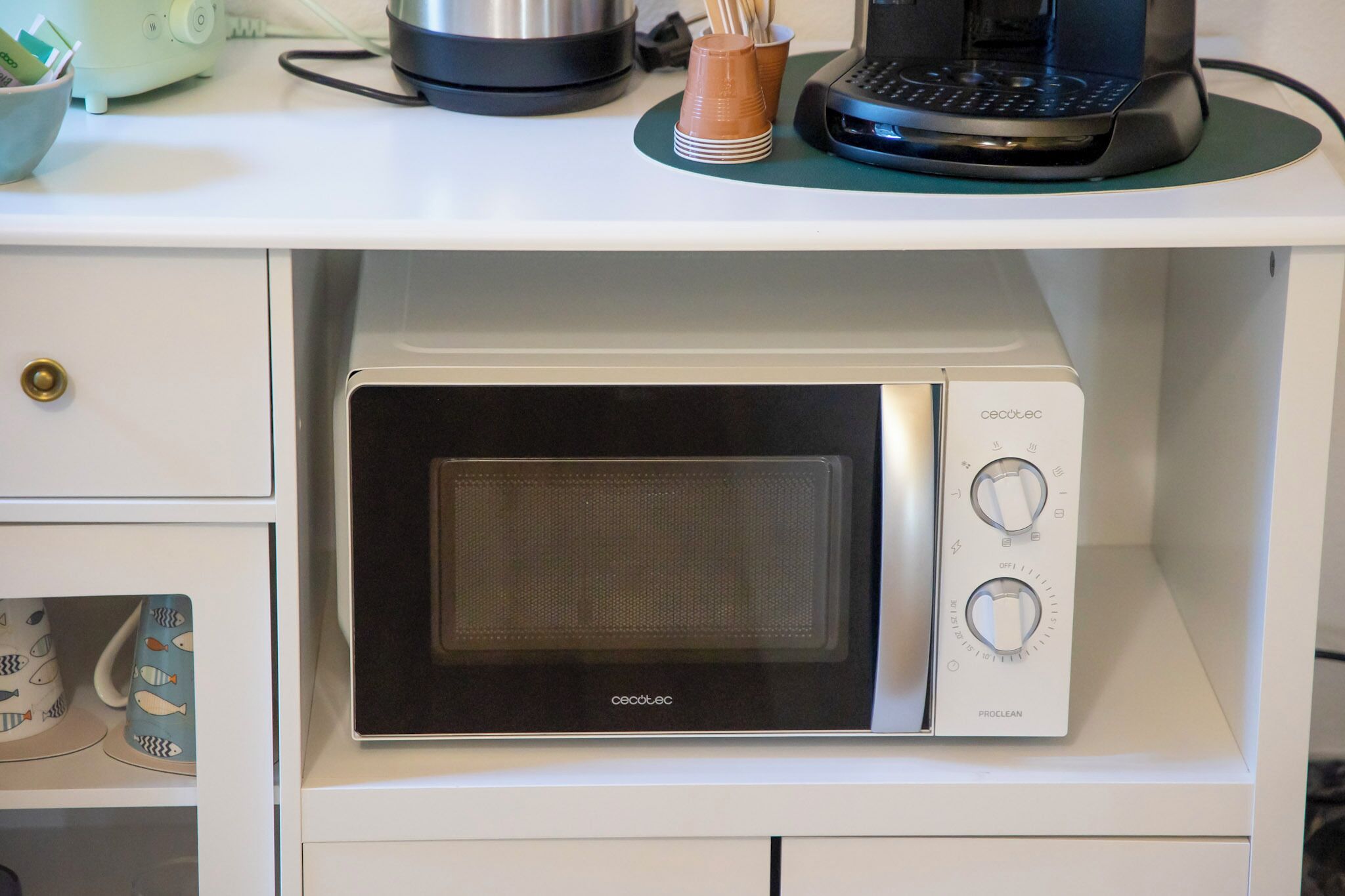 A microwave oven with a digital display and control knobs, placed on a white kitchen counter.