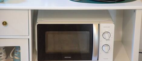 A microwave oven with a digital display and control knobs, placed on a white kitchen counter.