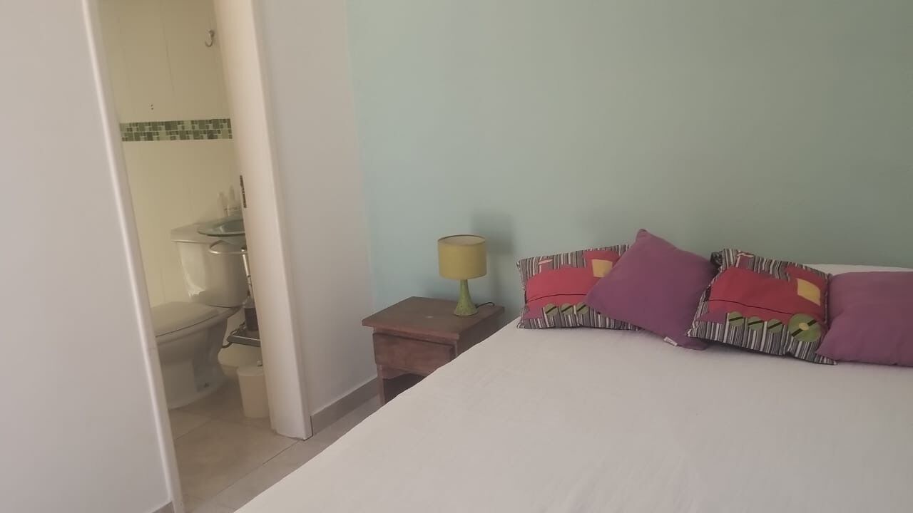 Une chambre à coucher avec un lit, une table de chevet avec une lampe et une vue sur la salle de bain.