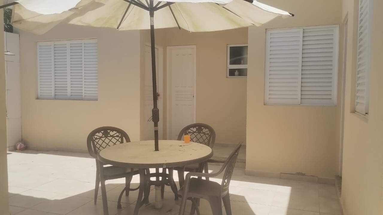 A patio with a round table and chairs, an umbrella, and a door.
