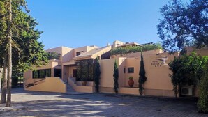 A hotel entrance with a paved driveway, a reception area, and a wall with a potted plant.