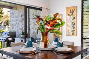 Ein Esstisch mit Tellern, Gläsern und einer Blumenvase.