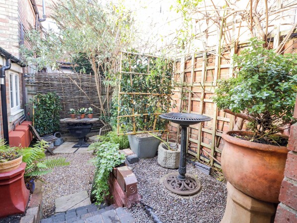 Ein Garten mit verschiedenen Pflanzen, einem Holzzaun und einem Metalltisch.