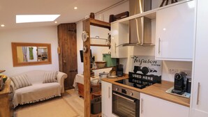 A compact kitchen with white cabinets, a built-in oven, and a coffee machine. - Tucked Away (Evesham)