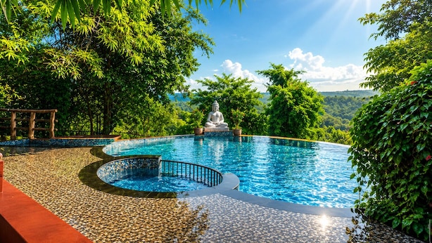 A serene infinity pool with a Buddha statue, surrounded by lush greenery and a clear sky. - Nature Trails Rock Valley Goa (Ponda)