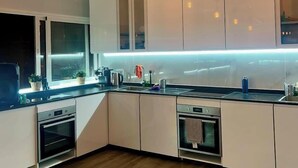A modern kitchen with white cabinets, a black countertop, and two pendant lights. - La Isleta Nest Hostel (Las Palmas de Gran Canaria)