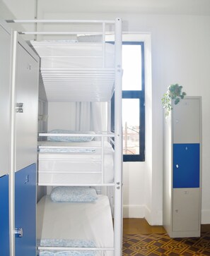 Dormitorio con literas, una ventana, una puerta y un armario azul.