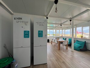 A modern kitchen with white cabinets, a fridge, and a freezer. There are signs with instructions and a note on the fridge. - La Isleta Nest Hostel (Las Palmas de Gran Canaria)