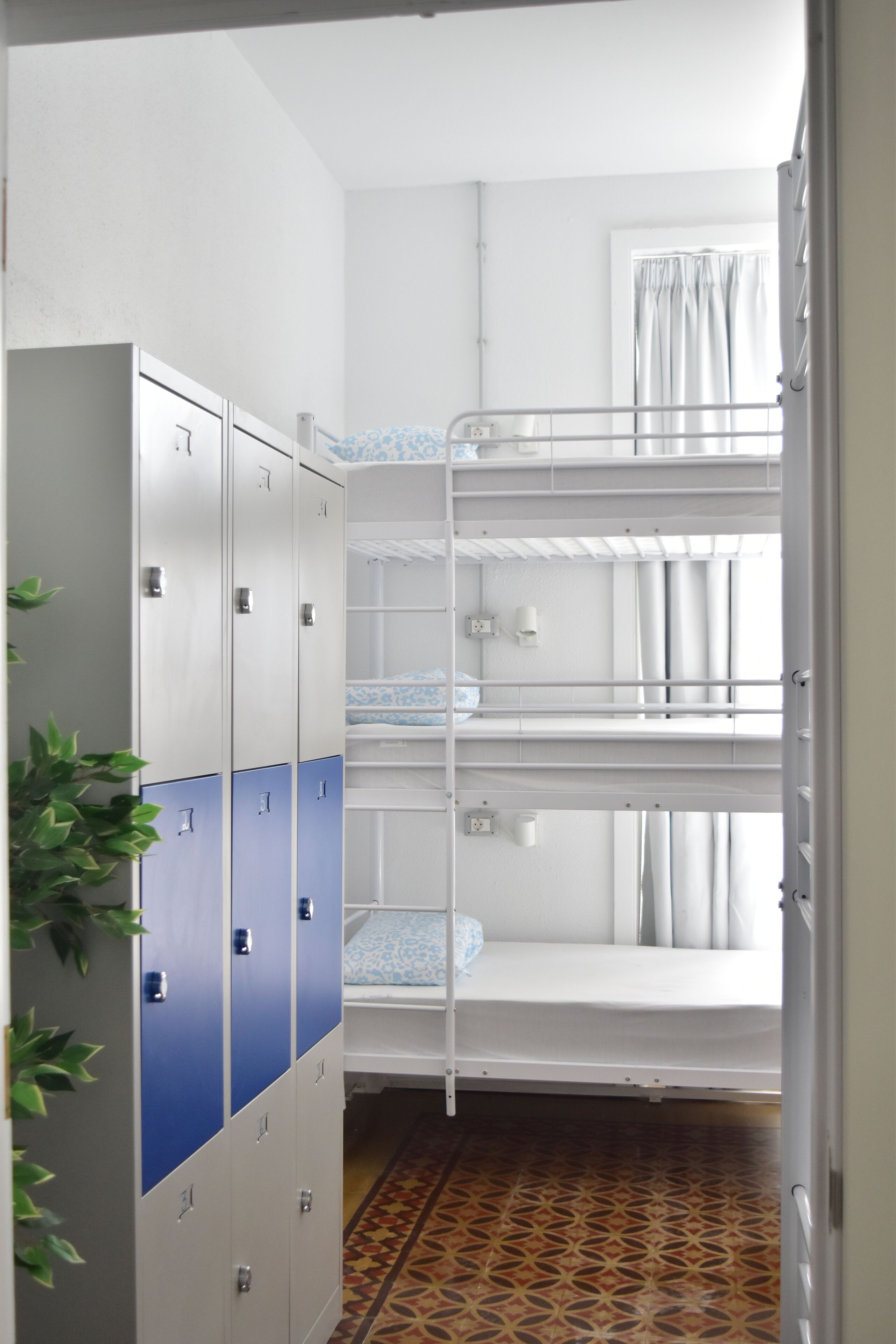 A dormitory room with bunk beds, a wardrobe, and a patterned floor.