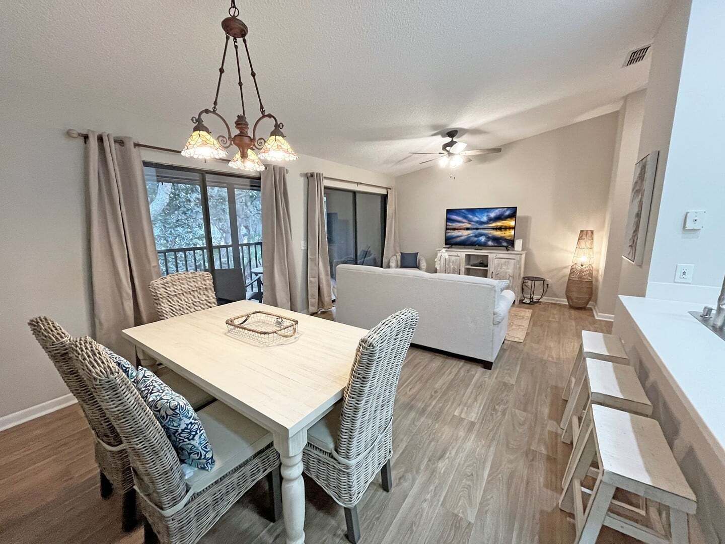 A dining area with a table and chairs, a sofa, a TV, and a ceiling fan.