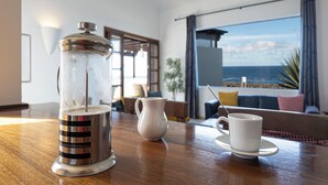 A kitchen area with a coffee maker, a pitcher, and a cup on a wooden table. - Puesta Del Sol (Montaña Roja)