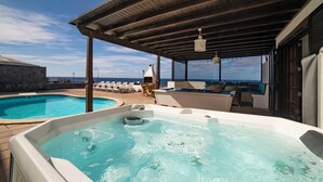 A rooftop pool area with a hot tub, lounge chairs, and a view of the ocean. - Puesta Del Sol (Montaña Roja)