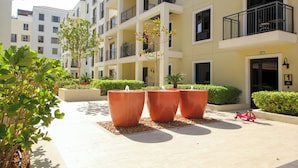 A courtyard with large terracotta planters, a red scooter, and a building with balconies and multiple windows.