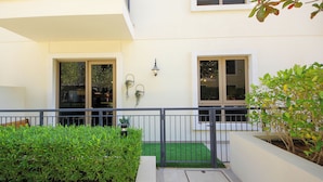 A modern building with a balcony, a small garden area, and a gated entrance.