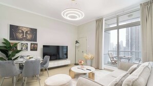 Una sala moderna con televisor de pantalla plana, comedor y un ventanal con vista a la ciudad.