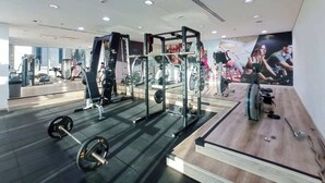 Un gimnasio moderno con diversos equipos de ejercicio, incluyendo un rack para sentadillas, bancos y una bicicleta estática.