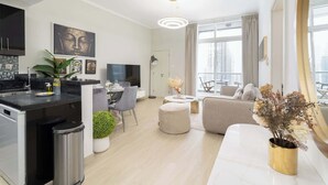 Un apartamento moderno con cocina, comedor y sala de estar. Cuenta con un ventanal grande, un televisor de pantalla plana y un sofá.