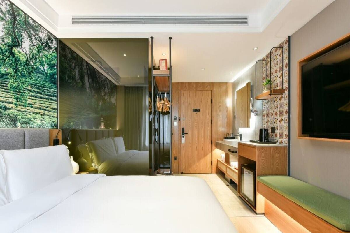 Un dormitorio moderno con una cama grande, un armario de madera, un baño con ducha y un televisor montado en la pared.