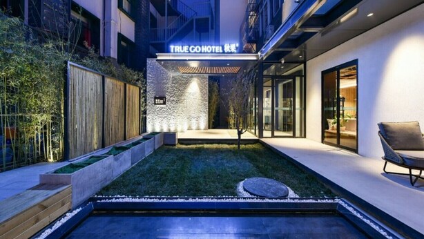 Un hôtel moderne avec une façade attrayante, une entrée bien éclairée, un petit jardin et une piscine.