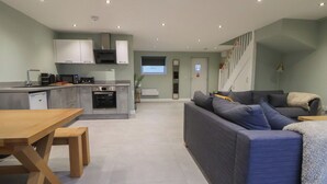 A modern kitchen with built-in appliances and a dining area with a wooden table and benches. - Oak Barn (Chester)
