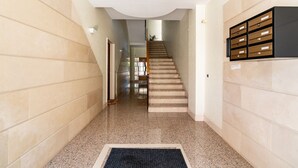 A hallway with a carpeted floor, a staircase, and a wall-mounted storage unit. - GuestHost - The House of Pines (Trani)