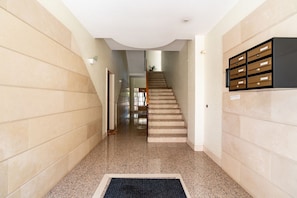 Ein Flur mit Teppichboden, einer Treppe und einem an der Wand befestigten Stauraum.