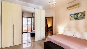 A bedroom with a bed, a wardrobe, a bench, a chandelier, and a painting on the wall. - GuestHost - The House of Pines (Trani)