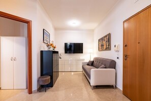 Ein modernes Wohnzimmer mit einer Couch, einem Fernseher, einem Schrank und einer Tür.