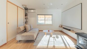 Un salon moderne comprenant un canapé, une table basse, une cheminée, une grande fenêtre et un téléviseur à écran plat.
