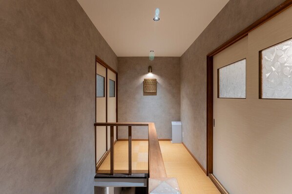 Un pasillo estrecho con suelo de madera, bajo techo y una pequeña mesa con un banco.