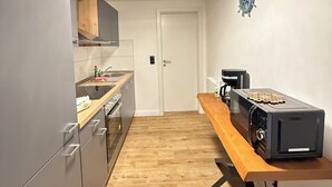 Een kleine keuken met een houten aanrecht, een koffieapparaat en een magnetron.