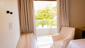 Ein Zimmer mit einem weißen Sessel, einem kleinen Tisch und einem Balkon mit weißer Brüstung.