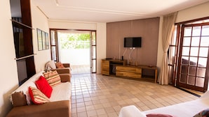 Ein Wohnzimmer mit Sofa, Fernseher und einer Schiebetür zu einem Außenbereich.