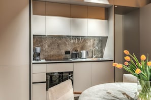 Cozinha moderna com eletrodomésticos embutidos, painel de fundo de mármore e área de jantar com mesa redonda e cadeiras.