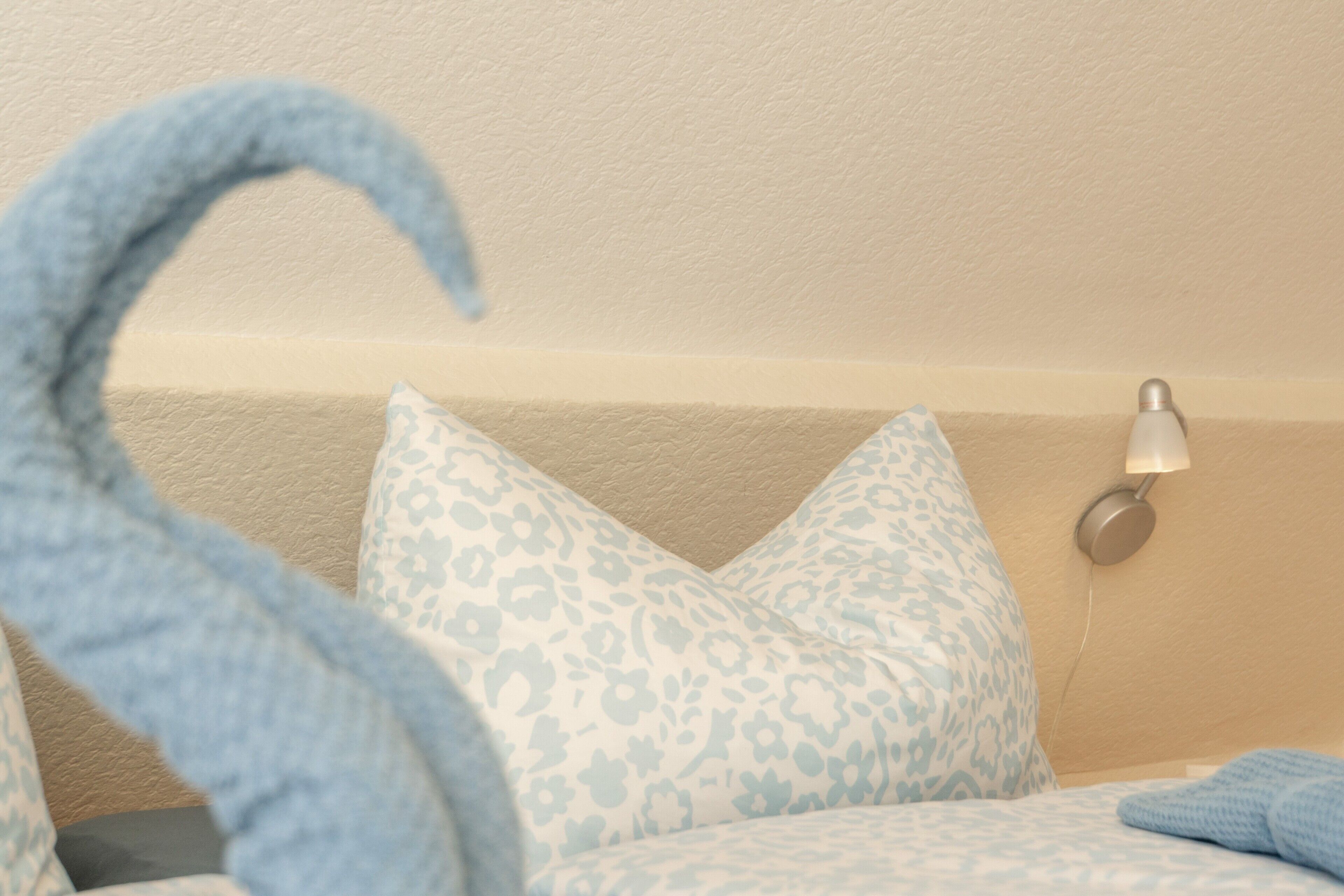 A bed with patterned pillows, a lamp, and a blue towel.