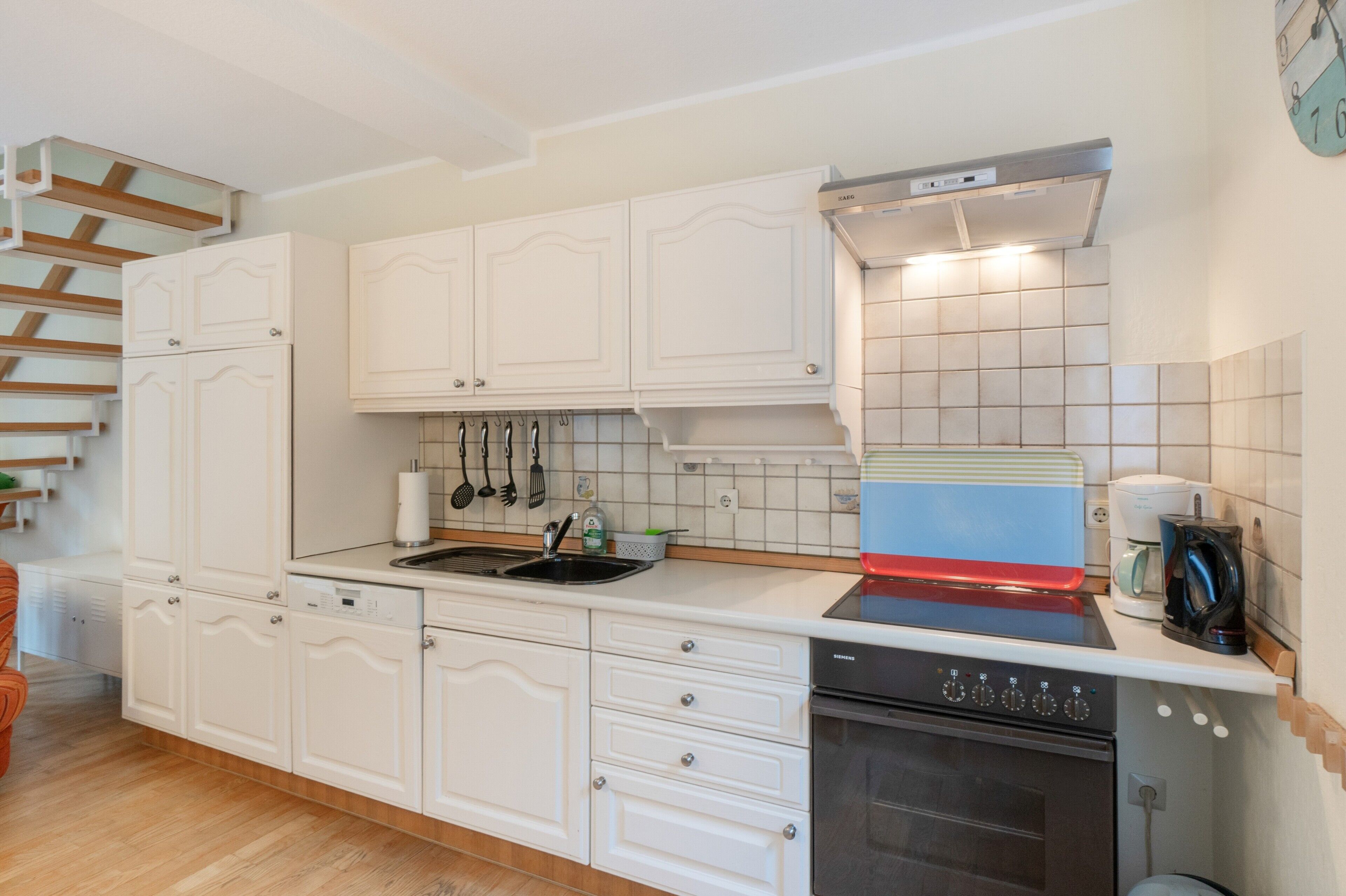 Eine Küche mit weißen Schränken, einer Edelstahl-Spüle, einem Geschirrspüler von Siemens und einem Backofen von Siemens.