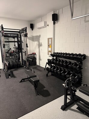 Et fitnessrum med en squat-stang, bænk, håndvægte og vægtskiver.