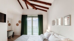 A bedroom with a bed, a desk, a chair, a TV, and a window with curtains. - <p><strong>Near the lake and the center (FLORIDA ASCONA Room 11)</strong></p><p>Just a few steps from the center and the charming lakeside promenade of Ascona, FLORIDA ASCONA Room 11 welcomes guests into a refined and comfortable setting, ideal for disco (Ascona)