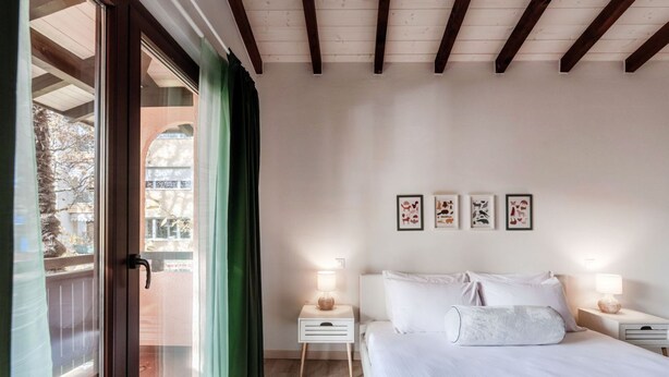 A bedroom with a bed, two bedside tables, a window with curtains, and framed pictures on the wall. - <p><strong>Near the lake and the center (FLORIDA ASCONA Room 11)</strong></p><p>Just a few steps from the center and the charming lakeside promenade of Ascona, FLORIDA ASCONA Room 11 welcomes guests into a refined and comfortable setting, ideal for disco (Ascona)