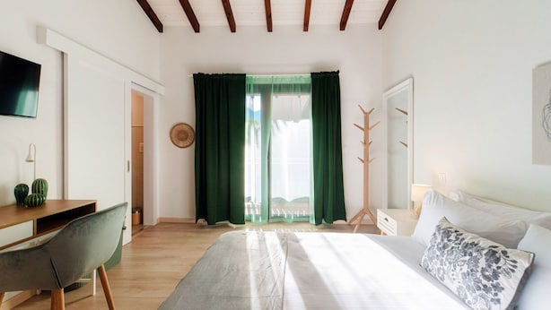 A bedroom with a bed, a desk, a chair, a coat rack, and a television. - <p><strong>Near the lake and the center (FLORIDA ASCONA Room 12)</strong></p><p>Just a few steps from the center and the charming lakeside promenade of Ascona, FLORIDA ASCONA Room 12 welcomes guests into a refined and comfortable setting, ideal for disco (Ascona)
