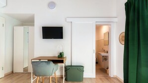 A room with a desk, chair, TV, and a view into a bathroom. - <p><strong>Near the lake and the center (FLORIDA ASCONA Room 12)</strong></p><p>Just a few steps from the center and the charming lakeside promenade of Ascona, FLORIDA ASCONA Room 12 welcomes guests into a refined and comfortable setting, ideal for disco (Ascona)